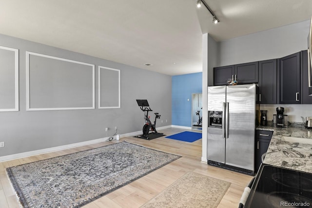 kitchen with stainless steel fridge, light wood-style flooring, black / electric stove, and rail lighting