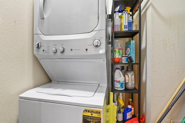 clothes washing area featuring stacked washer / drying machine and a textured wall