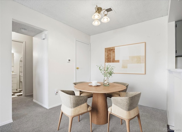 carpeted dining space featuring a textured ceiling and baseboards