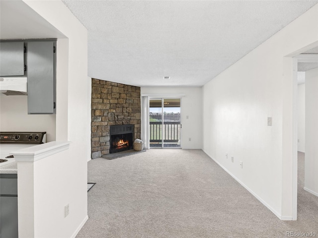 unfurnished living room featuring carpet floors, a fireplace, a textured ceiling, and baseboards
