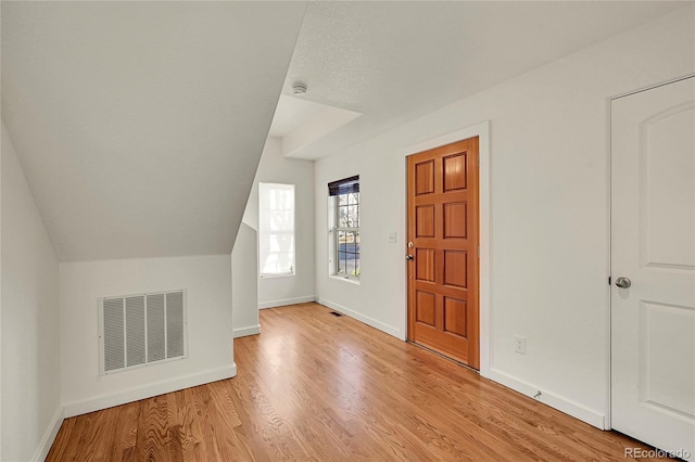 additional living space featuring lofted ceiling and light wood-type flooring