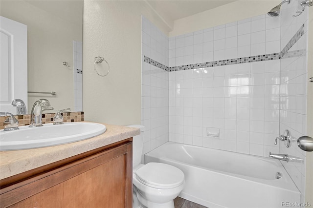 full bathroom featuring vanity, tiled shower / bath combo, and toilet