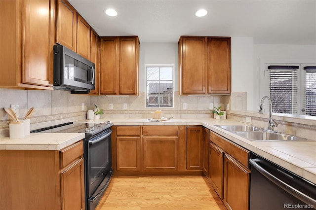 kitchen featuring decorative backsplash, light wood-type flooring, sink, and appliances with stainless steel finishes