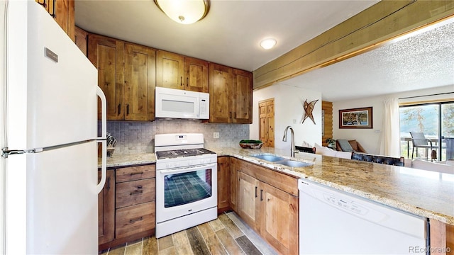 144 Tall Pine Cir, Grand Lake, CO 80447 - kitchen with white appliances, a sink, decorative backsplash, a peninsula, and brown cabinets