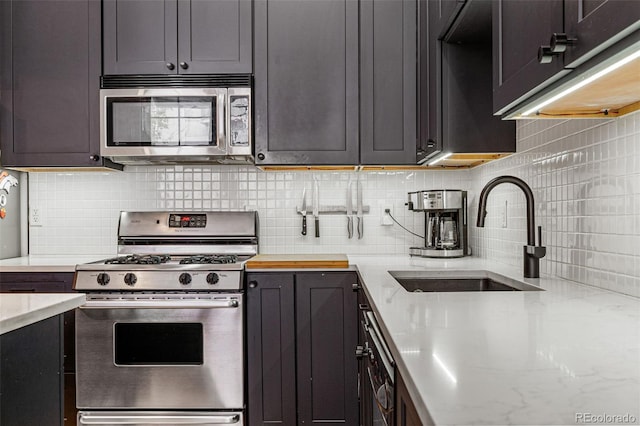 kitchen with light stone counters, appliances with stainless steel finishes, sink, and decorative backsplash