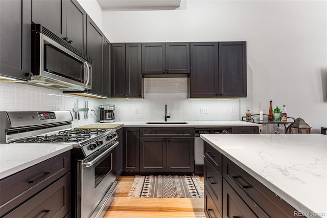 kitchen featuring light hardwood / wood-style floors, appliances with stainless steel finishes, sink, and decorative backsplash