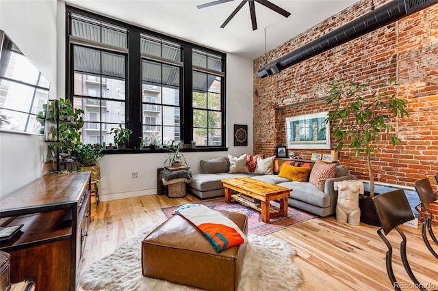 living room with ceiling fan, hardwood / wood-style flooring, and brick wall