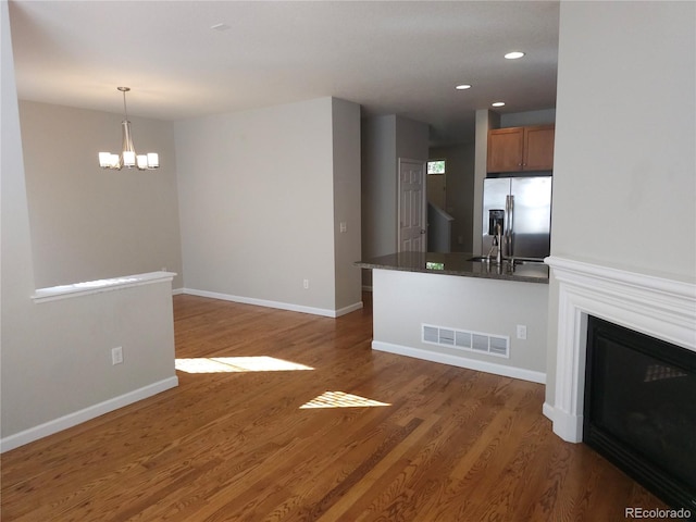 unfurnished living room featuring dark wood-type flooring, sink, and an inviting chandelier