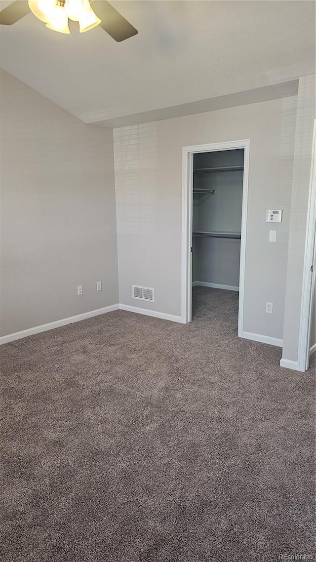 unfurnished bedroom with a spacious closet, a closet, ceiling fan, and carpet flooring