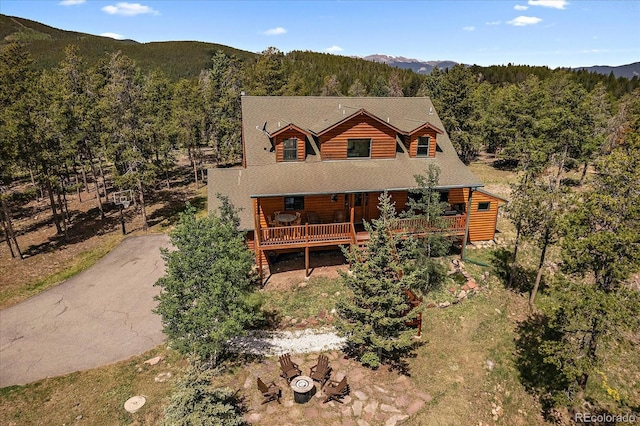 log-style house with a mountain view, aphalt driveway, faux log siding, and a view of trees