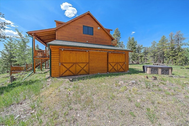 back of house with log veneer siding, an outdoor structure, and a barn