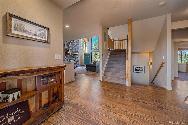 staircase with a fireplace, wood finished floors, and a textured wall