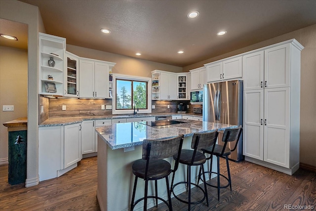 kitchen featuring light stone countertops, backsplash, white cabinets, a center island, and dark hardwood / wood-style floors