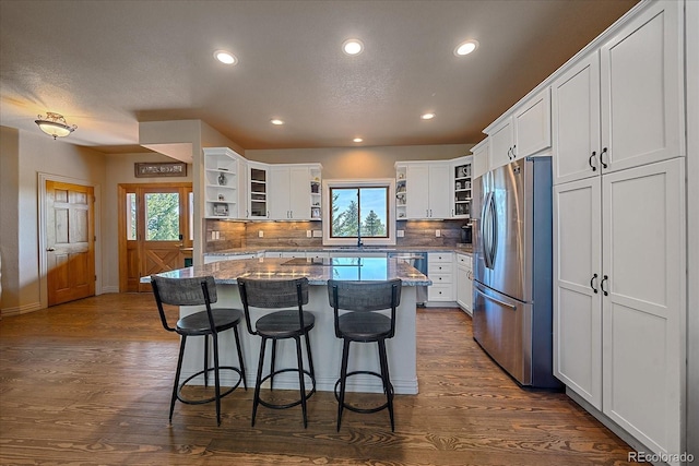 kitchen with white cabinetry, dark wood-type flooring, stainless steel appliances, a kitchen breakfast bar, and a kitchen island