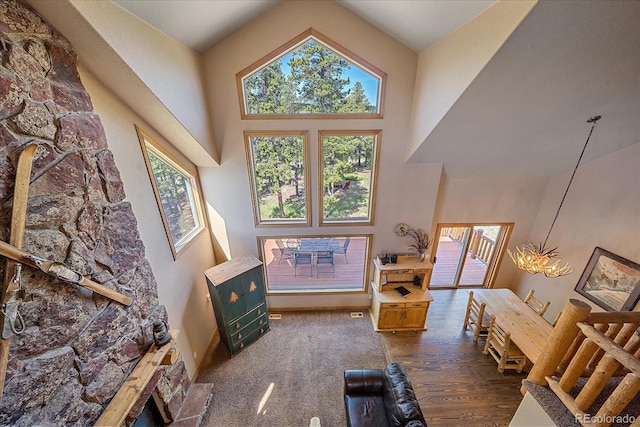 living room featuring a healthy amount of sunlight, dark wood-type flooring, high vaulted ceiling, and a chandelier