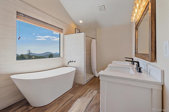 full bathroom with vanity, wood finished floors, a tile shower, a freestanding bath, and vaulted ceiling