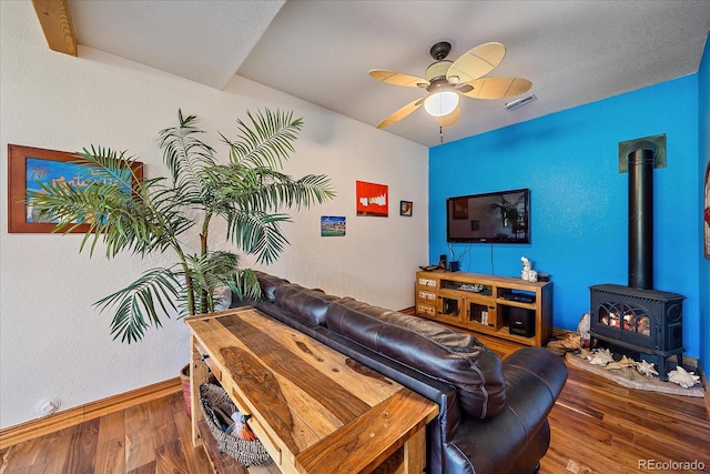 living room featuring hardwood / wood-style flooring, a wood stove, and ceiling fan