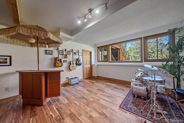 interior space featuring a textured ceiling, light wood-type flooring, and baseboards