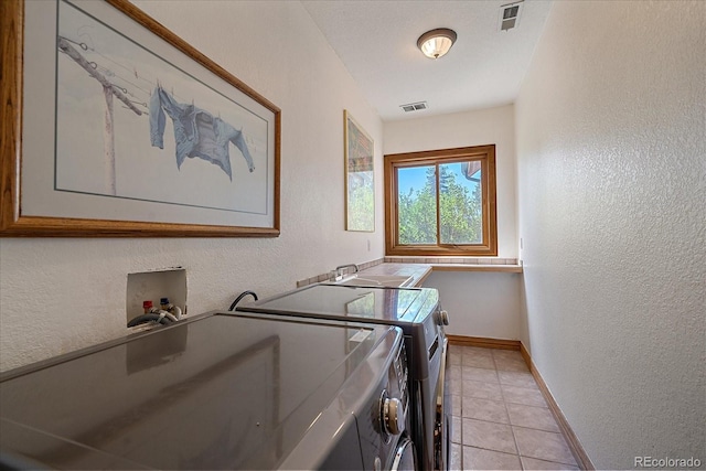 washroom featuring a textured wall, visible vents, and independent washer and dryer