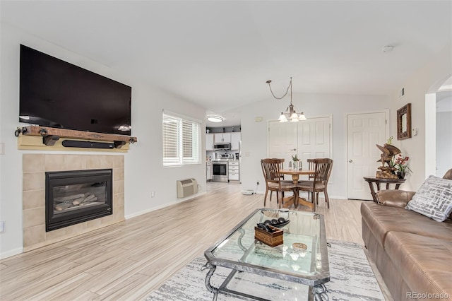 living room with an inviting chandelier, light hardwood / wood-style floors, a wall unit AC, and a tiled fireplace