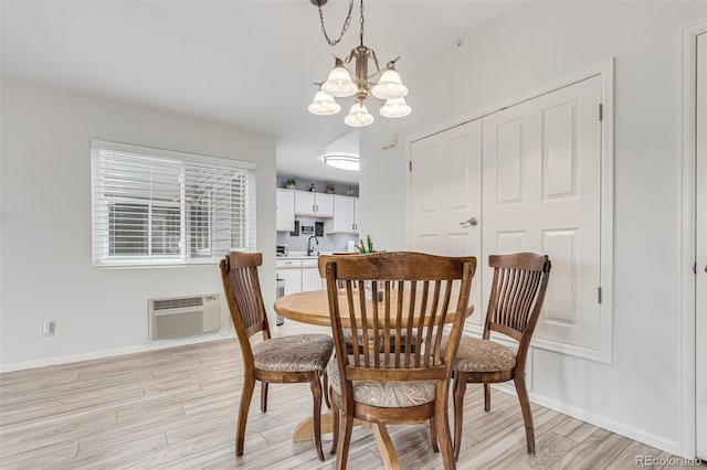 dining area featuring an AC wall unit, sink, light hardwood / wood-style flooring, and a notable chandelier