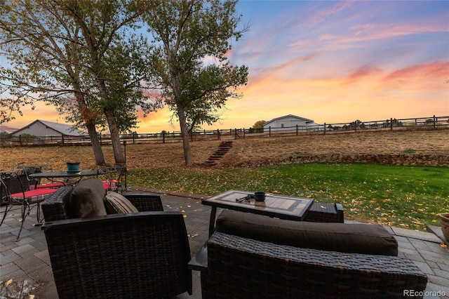 patio terrace at dusk with a rural view and a lawn