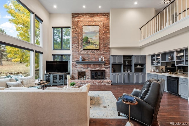 living room with a fireplace, a towering ceiling, and dark wood-type flooring