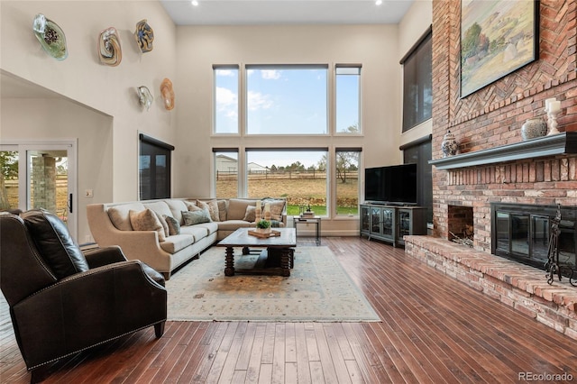 living room featuring a fireplace, a towering ceiling, and dark hardwood / wood-style floors