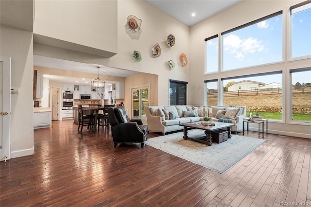 living room with dark hardwood / wood-style flooring, a towering ceiling, and a healthy amount of sunlight