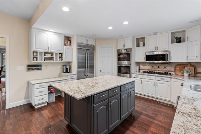 kitchen with light stone counters, white cabinets, dark hardwood / wood-style floors, and appliances with stainless steel finishes