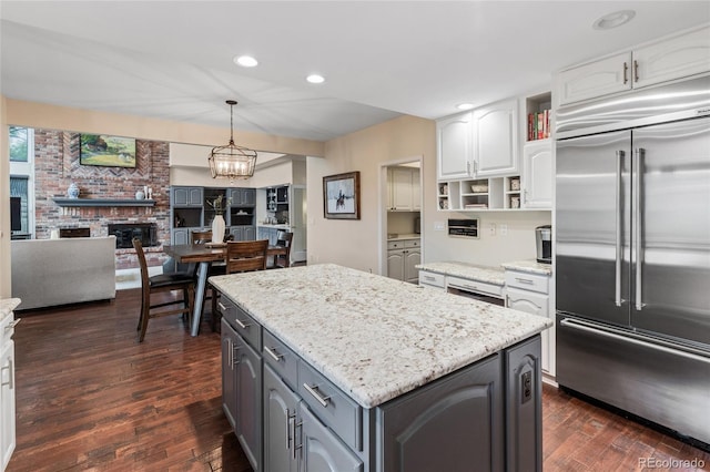 kitchen featuring dark hardwood / wood-style flooring, white cabinets, decorative light fixtures, and stainless steel built in refrigerator