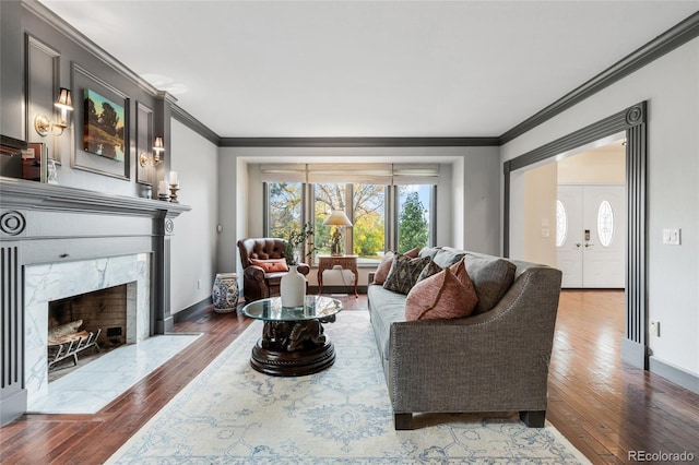 living room with a high end fireplace, crown molding, and dark wood-type flooring