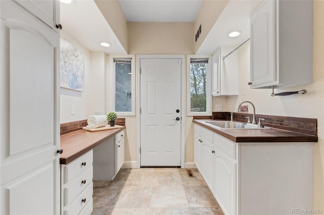 kitchen featuring butcher block countertops, white cabinetry, and sink