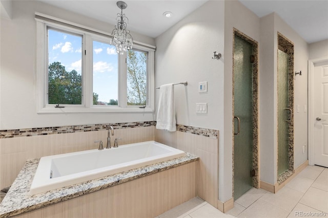 bathroom featuring tile patterned floors, tile walls, independent shower and bath, and a chandelier