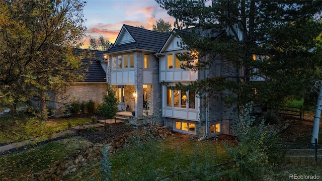 back house at dusk featuring a balcony