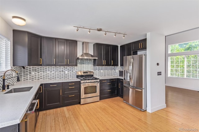 4935 Apollo Bay Dr, Highlands Ranch, CO 80130 - kitchen featuring stainless steel appliances, wall chimney range hood, a sink, decorative backsplash, and light wood-style floors
