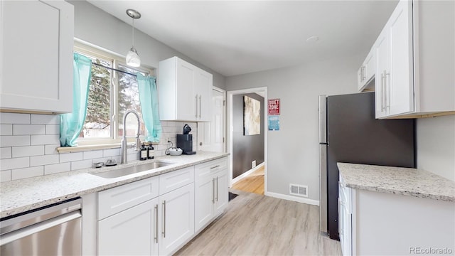 kitchen with sink, light hardwood / wood-style flooring, backsplash, white cabinets, and appliances with stainless steel finishes