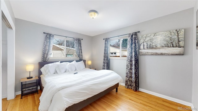 bedroom featuring hardwood / wood-style floors, a closet, and multiple windows