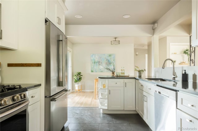 654 S Shoshone St, Denver, CO 80223 - kitchen featuring stainless steel appliances, a sink, dark countertops, white cabinetry, and recessed lighting