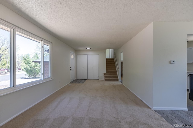 3256 S Nucla St, Aurora, CO 80013 - foyer entrance featuring a textured ceiling, baseboards, stairway, and light carpet