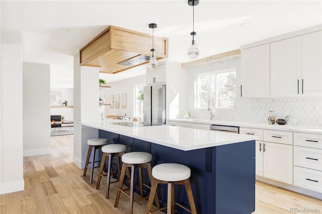 kitchen featuring stainless steel appliances, a kitchen breakfast bar, white cabinets, and light wood-style floors
