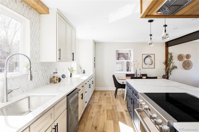 kitchen featuring a sink, stainless steel appliances, white cabinets, light wood-style flooring, and light stone countertops
