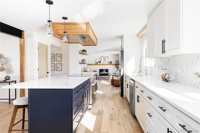 kitchen featuring a sink, blue cabinetry, appliances with stainless steel finishes, light wood-type flooring, and open floor plan