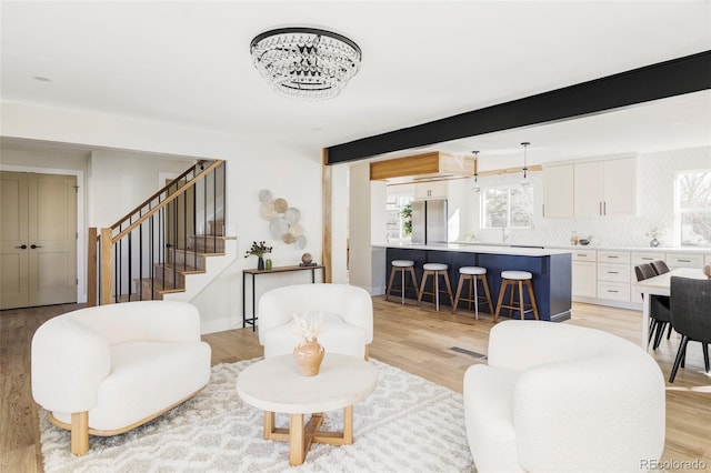 living room with light wood finished floors, stairs, and beam ceiling