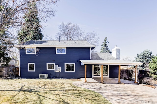rear view of house with central AC unit, a chimney, and a patio
