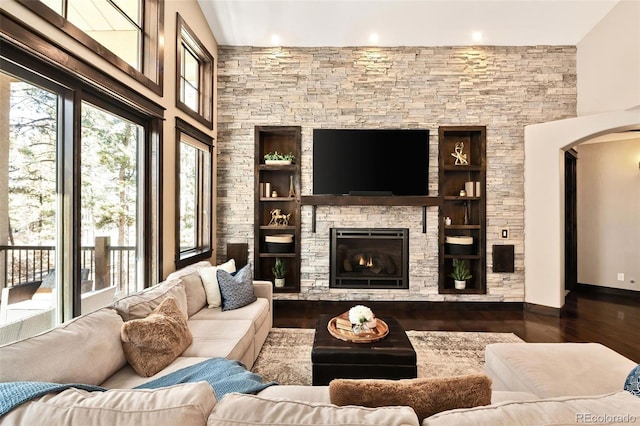 living room featuring a stone fireplace, baseboards, and wood finished floors