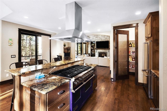 kitchen with premium appliances, a kitchen breakfast bar, island exhaust hood, and dark wood-type flooring