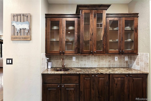 bar with a sink, tasteful backsplash, and a textured wall