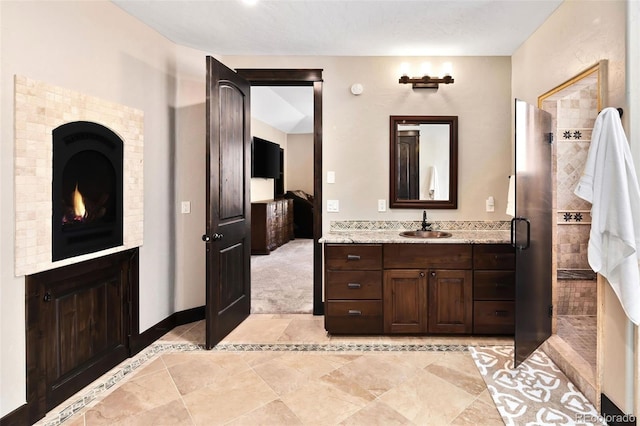 bathroom with baseboards, vanity, and a tile shower