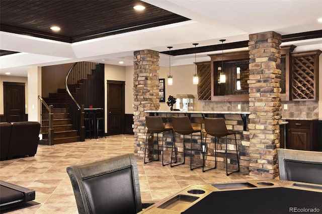 bar featuring stairs, wooden ceiling, hanging light fixtures, a raised ceiling, and ornate columns